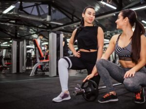 "Beautiful young asian woman stand on one knee and look at her friend. She holds one hand on her leg. She youches weight."